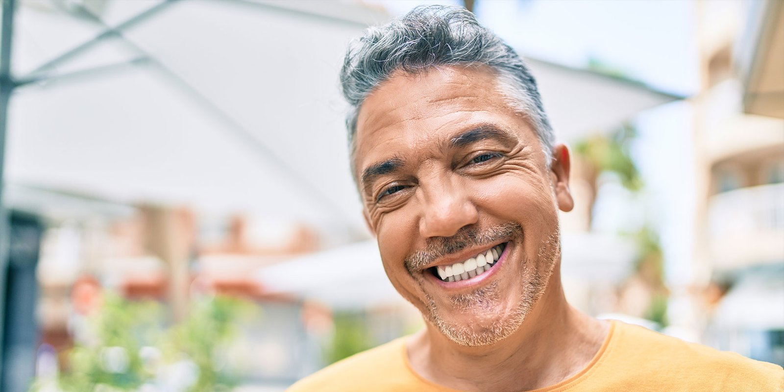 middle age person smiling brightly outside in the town area