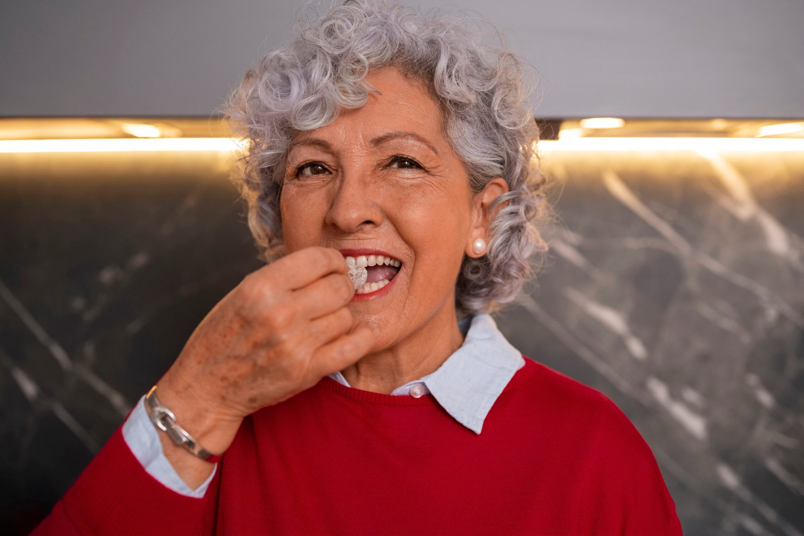 senior woman enjoying fruit after dental implant treatment
